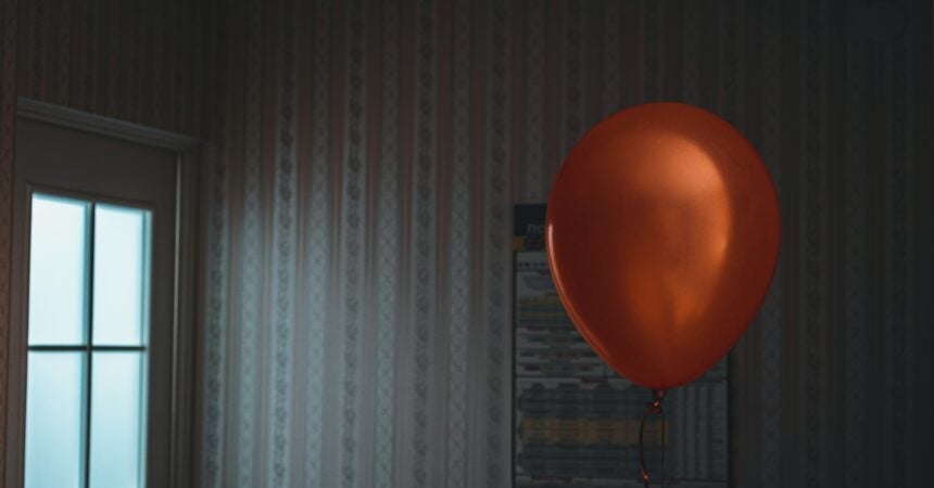 A red balloon floating alone in an abandoned room