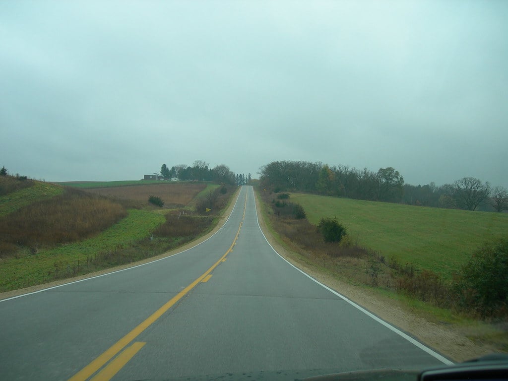 A long road with fields on either side