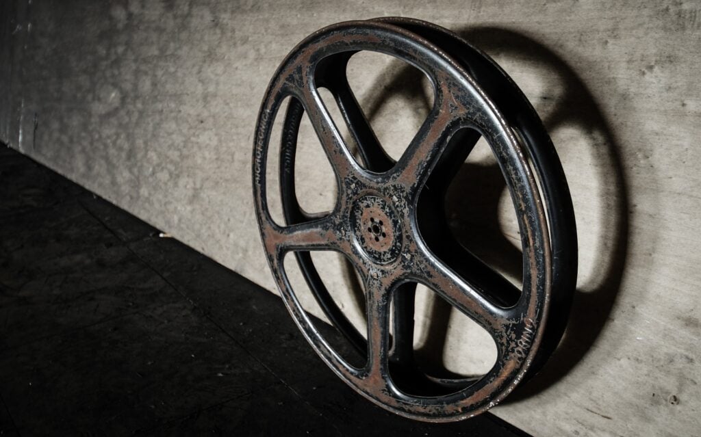 An old, empty film reel leaning abandoned against a wall