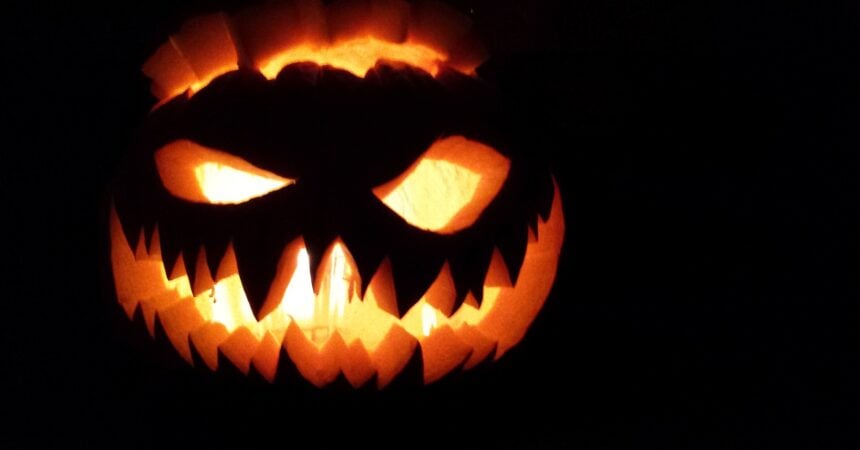A jack o' lantern with sharp teeth, lit, in the dark