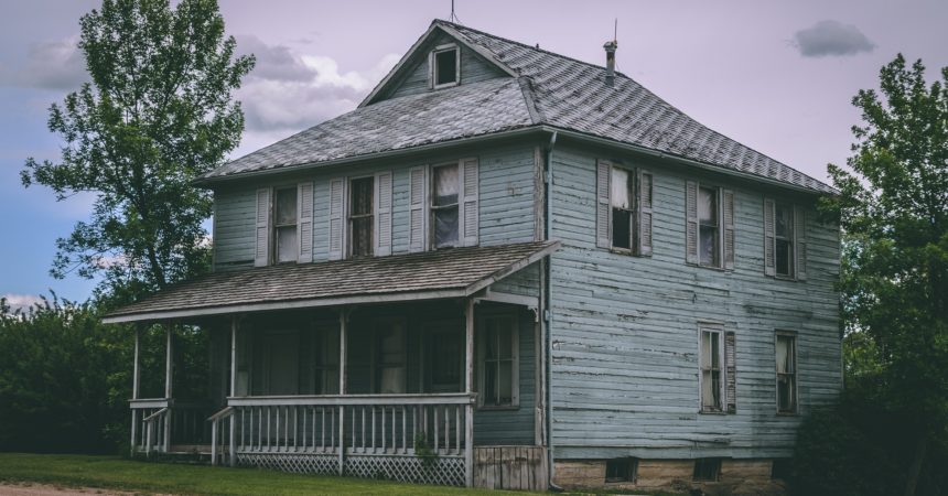 An abandoned, two-story single-family house with a porch