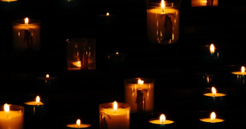 A large quantity of lit candles glowing in the darkness