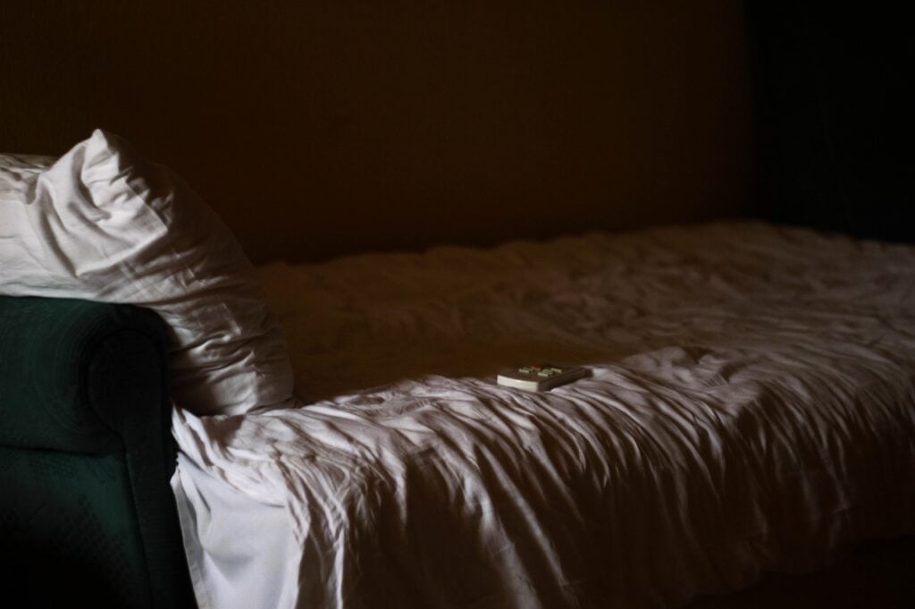 A bed, partially in shadow in a dark room