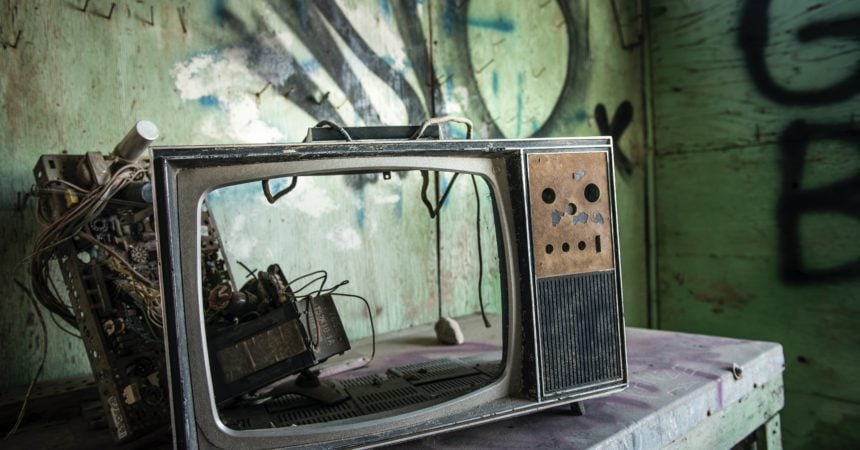 An abandoned, vintage television with a busted-out screen