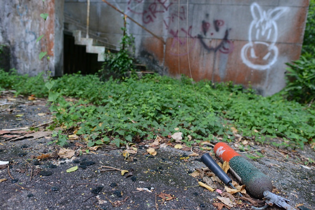 A fire extinguisher on the ground outside the abandoned hostel