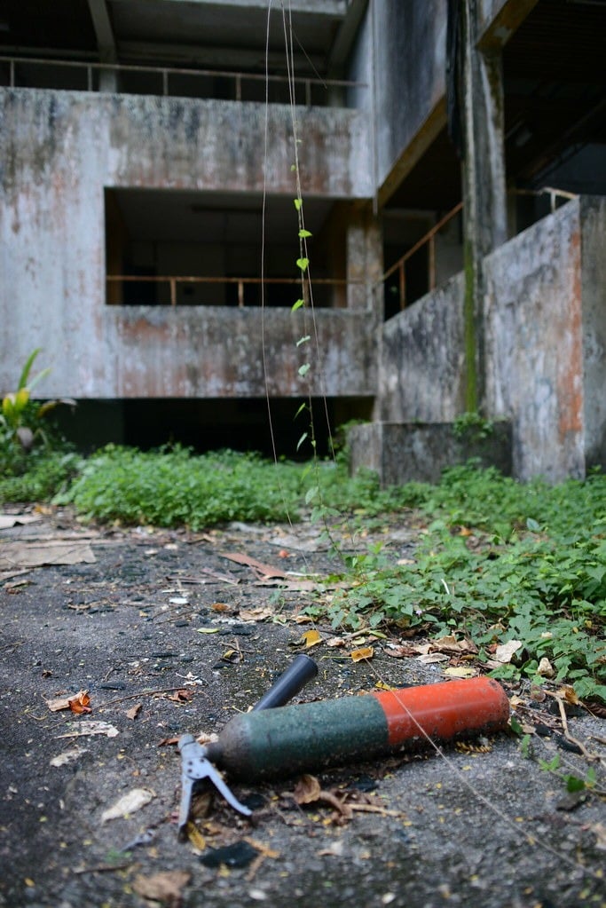 A fire extinguisher on the ground outside at the abandoned hostel