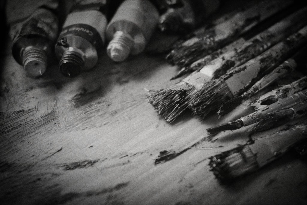 A black and white photograph of dirty paintbrushes