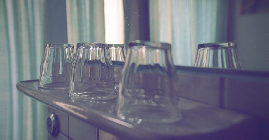 Three old drinking glasses arranged upside down on a shelf