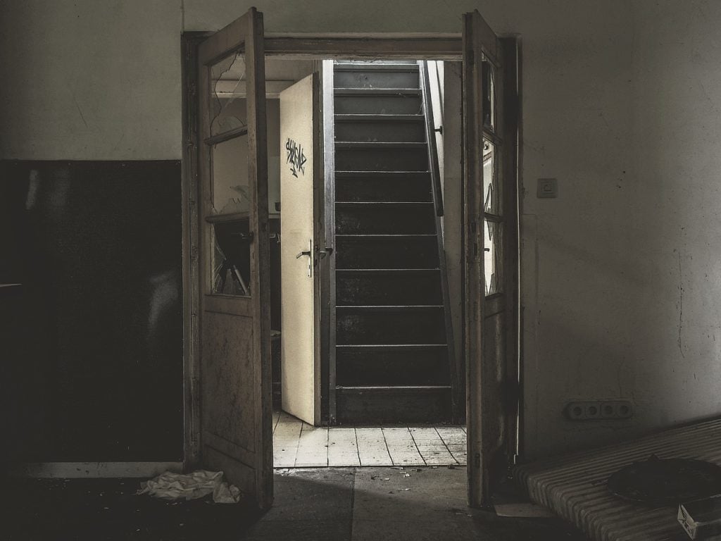 A staircase viewed through a door in an abandoned building