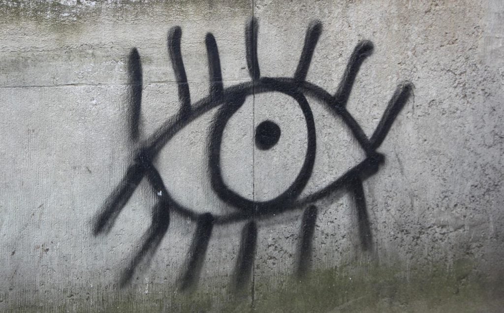 A graffiti drawing of an eye on a cement wall