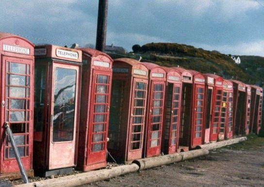 A line of defunct British phone boxes