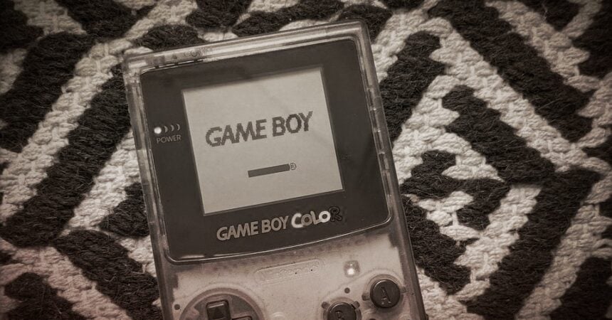 A black and white photo of a Game Boy Color console against a geometric patterned background