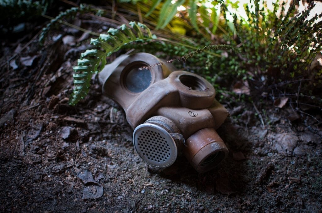 A gas mask lying on the ground in the woods