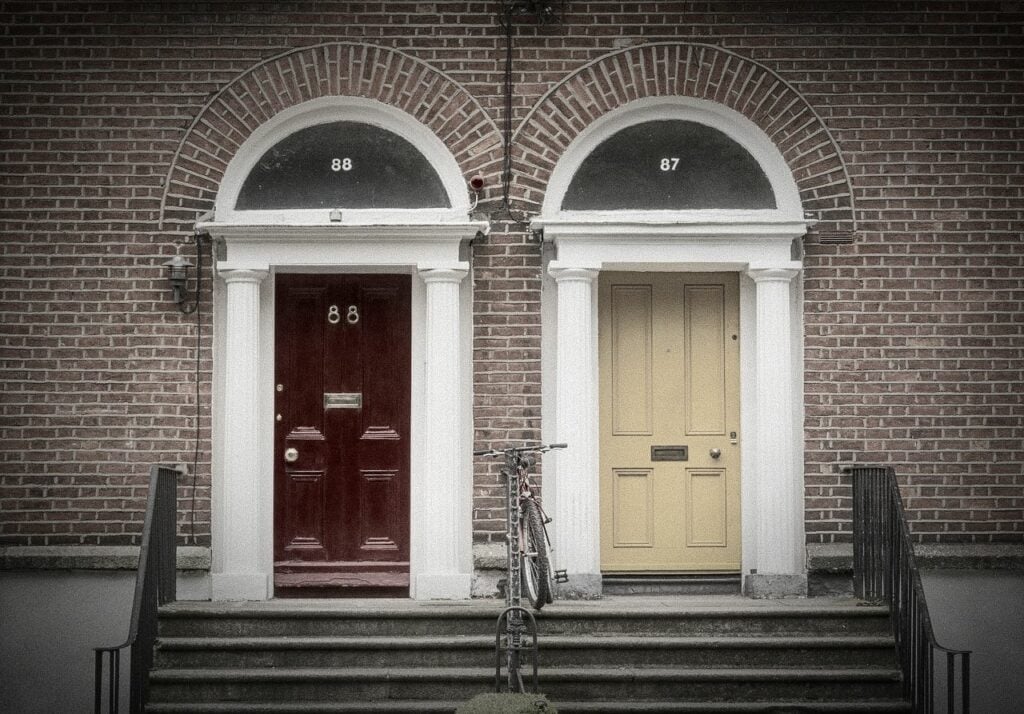 A red door and a yellow door, next to each other set in a brick wall