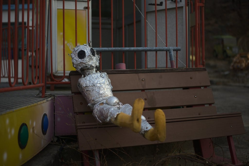 An alien figure sitting on a bench at Yongma Land