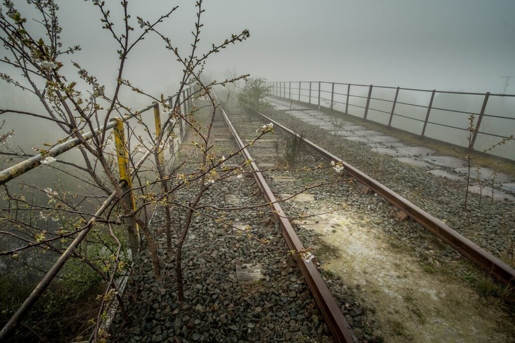 train tracks over a bridge in the fog