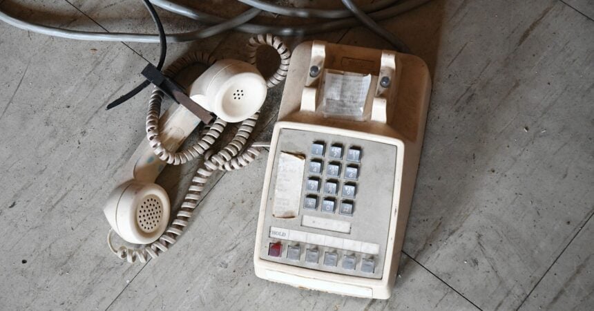 a white push button telephone, dusty and sitting on the floor