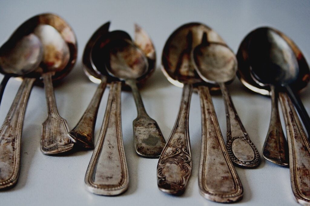 a eight rusted, old spoons lying on a flat, white surface