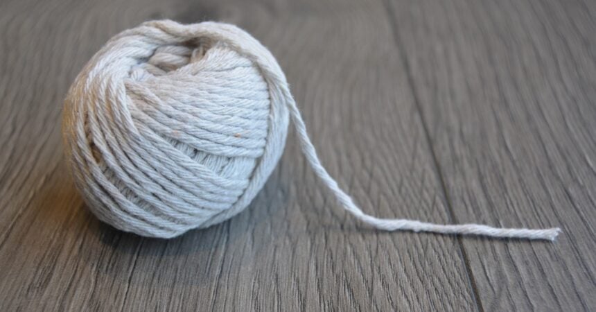 a ball of white twine sitting on a wood surface