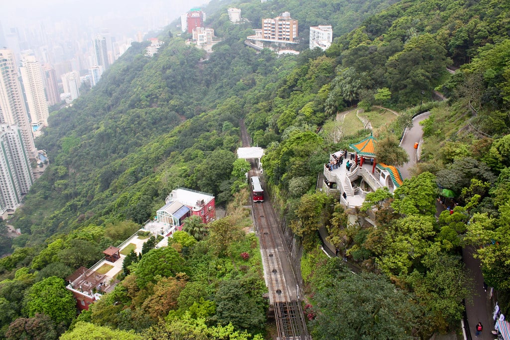 The view of the Peak Tram, a green funicular, on its track surrounded by forest