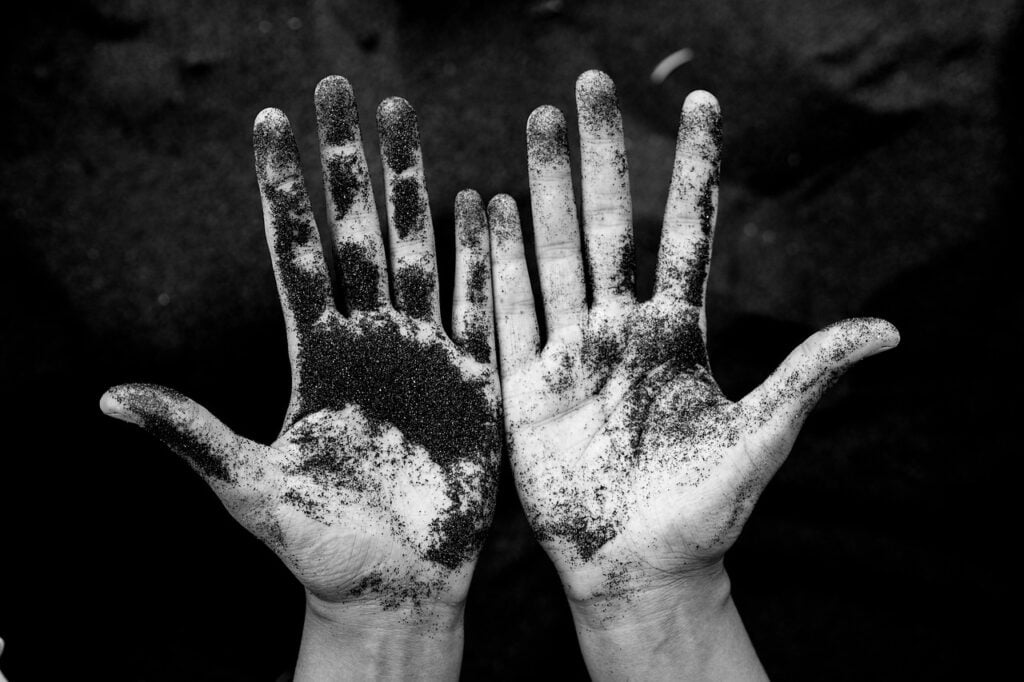 two hands, palms facing us, covered in dirt