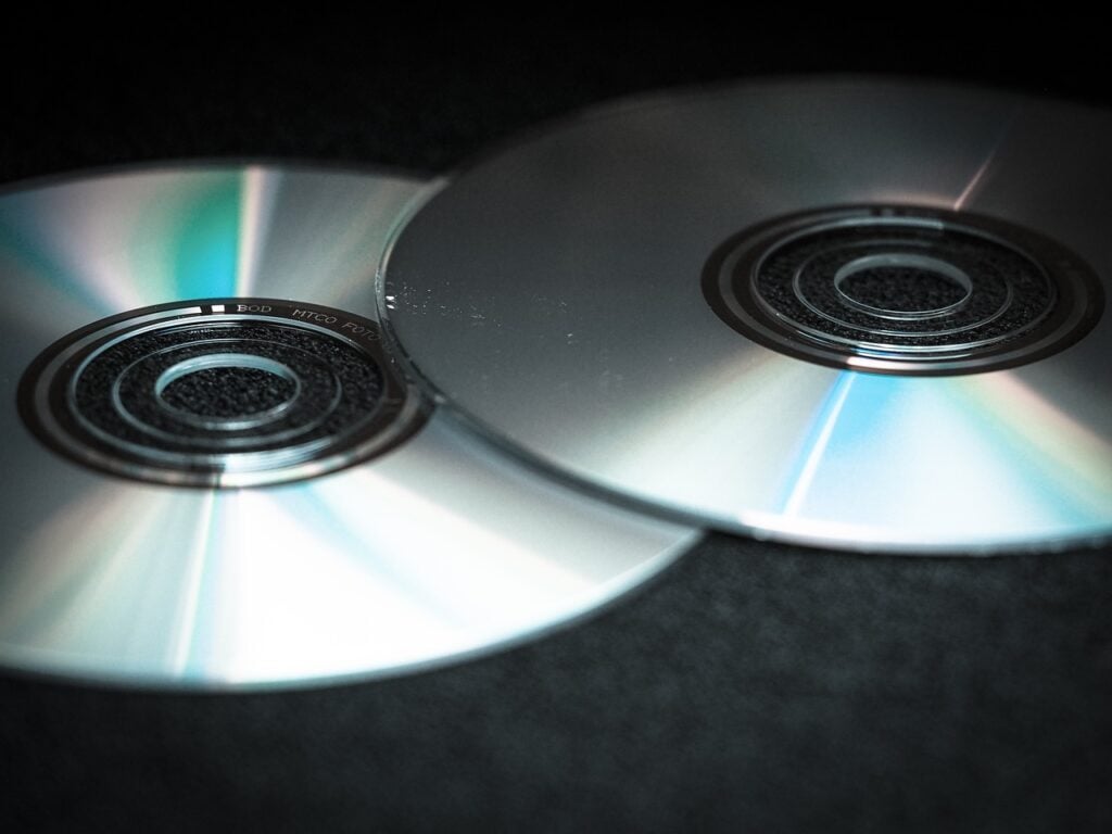 two CDs, overlapping slightly, on a dark surface