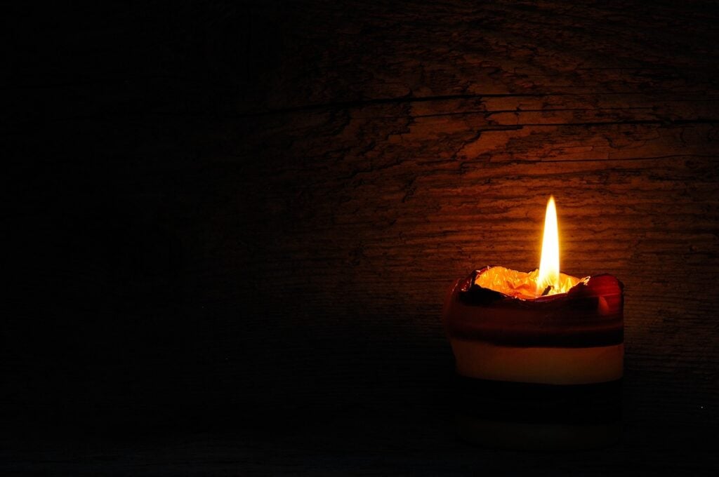 a small tea light, flame glowing in an otherwise dark room