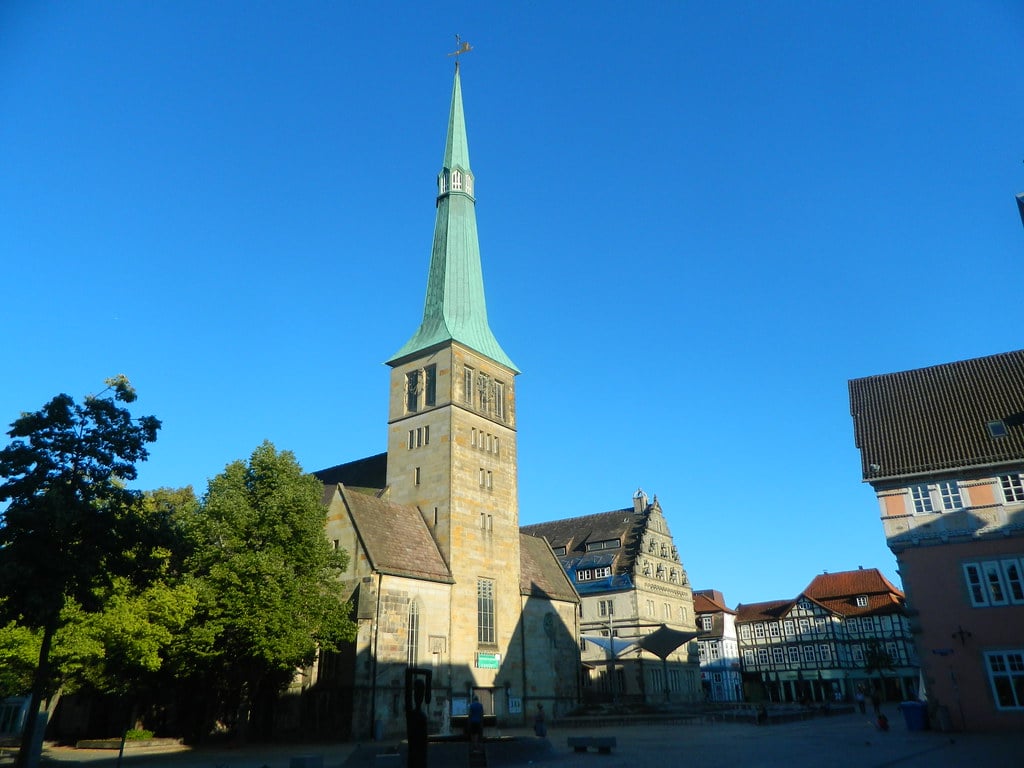 the spire of the market church in hameln, germany, set against a bright blue sky