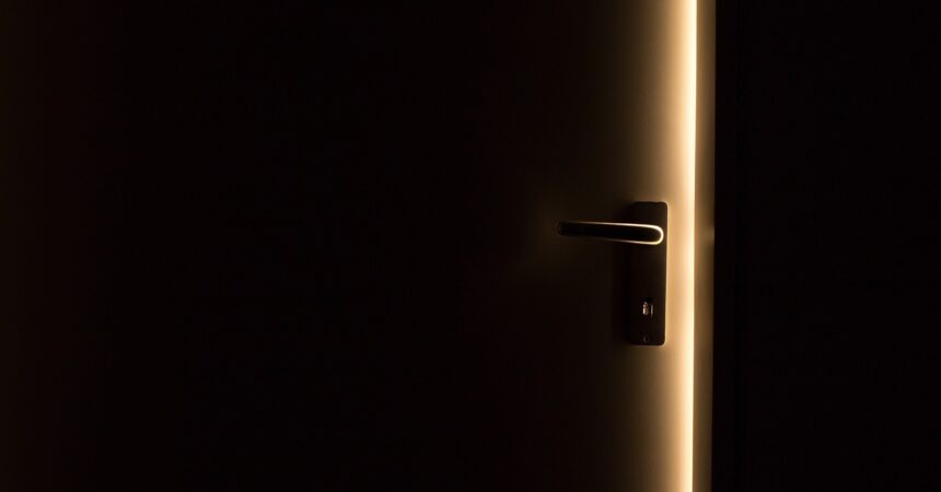a dark door, cracked open to reveal a sliver of light