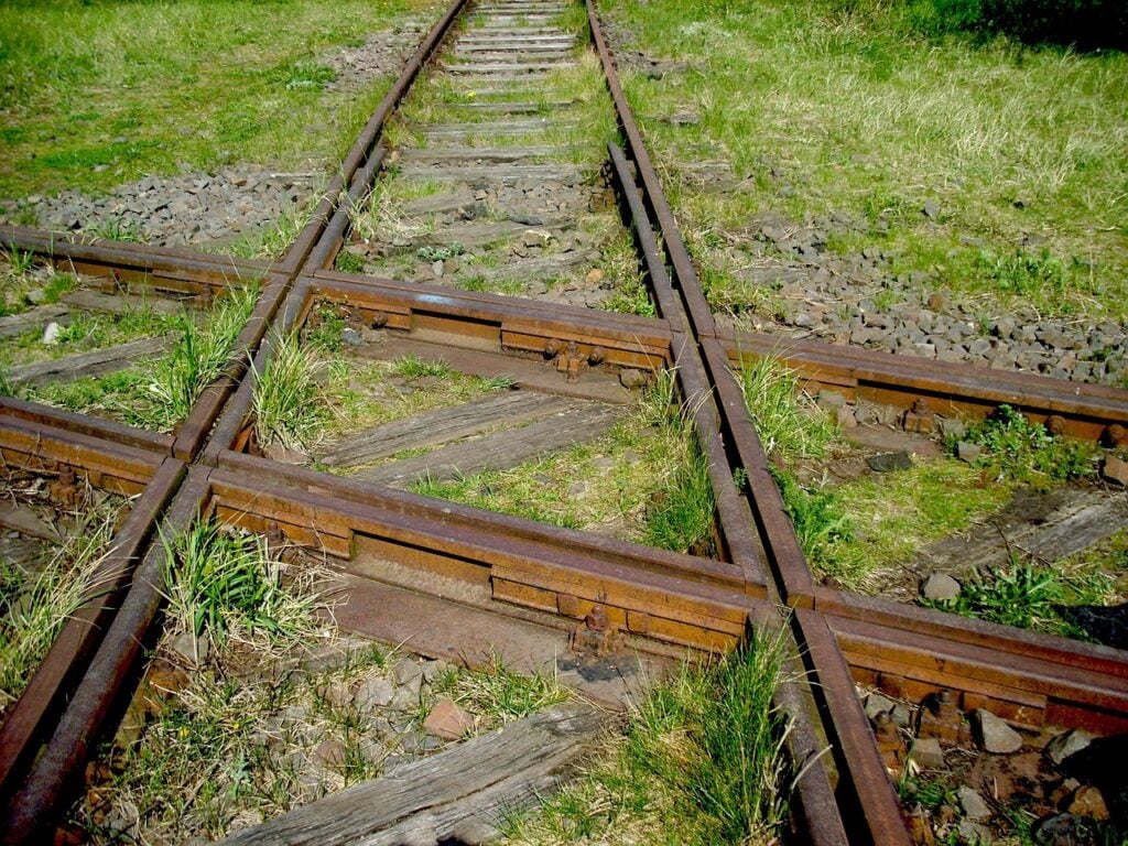 the junction of two train tracks, with lots of grass around. rural and lonely