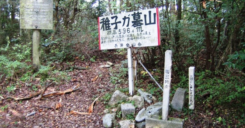 a sign in japanese in a forested, mountainous setting