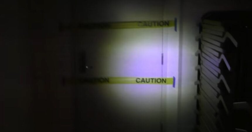 a grainy screenshot from a video of a white door with yellow caution tape blocking it off