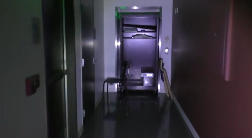 an elevator blocked by old school furniture in a dark hallway