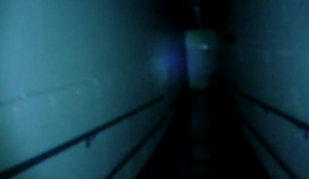 a dark, grainy image of an institutional hallway in the dark