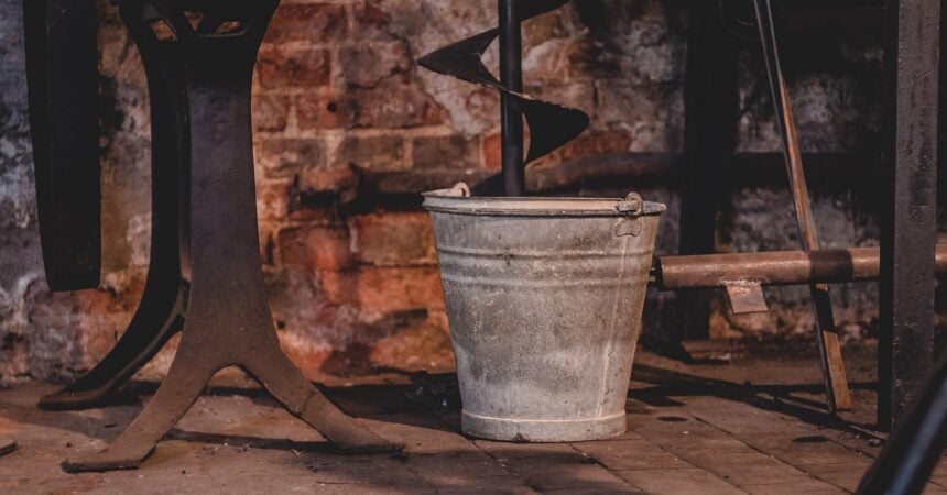 a rusty metal bucket in an abandoned building set against a brick wall