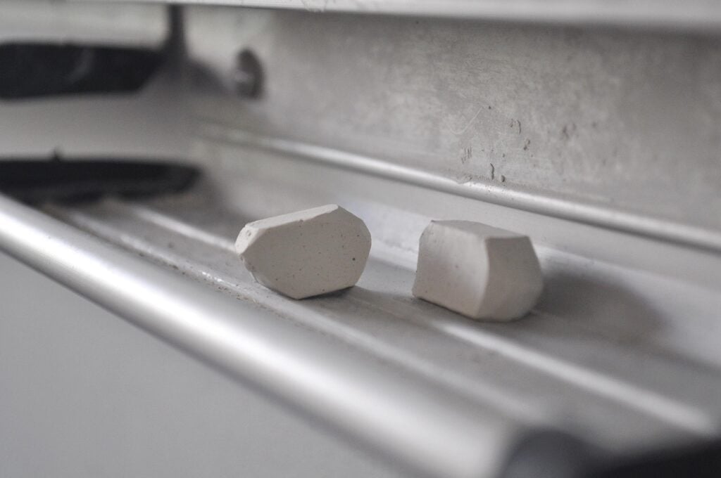 two pieces of chunky white chalk in the chalk tray of a blackboard