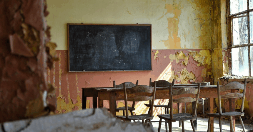 an old, abandoned classroom with a blackboard and old-fashioned wood desks and chairs