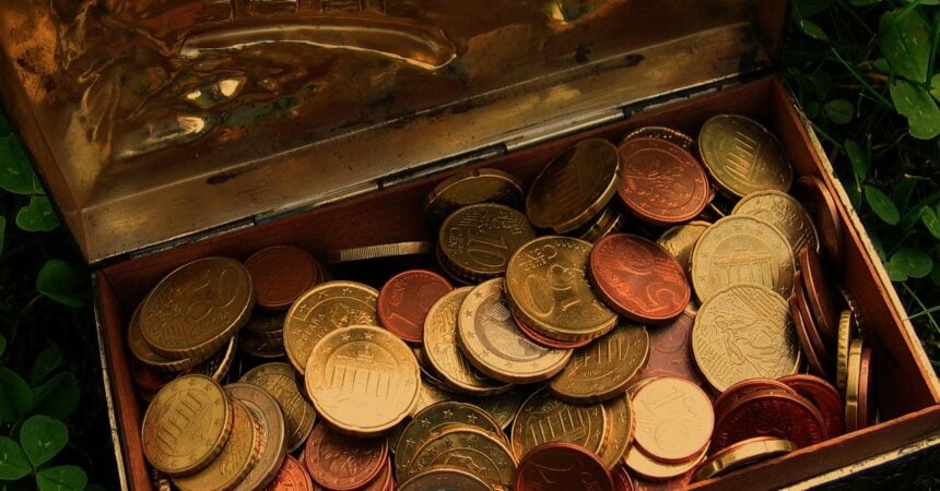 overhead view of lots of coins of many different currencies in a metal box with the lid open