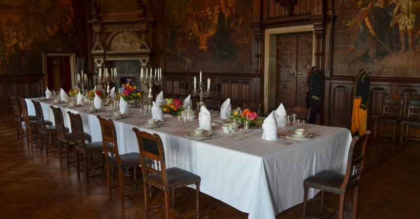 an ornate, wood-paneled dining room with a long table set for a dinner party