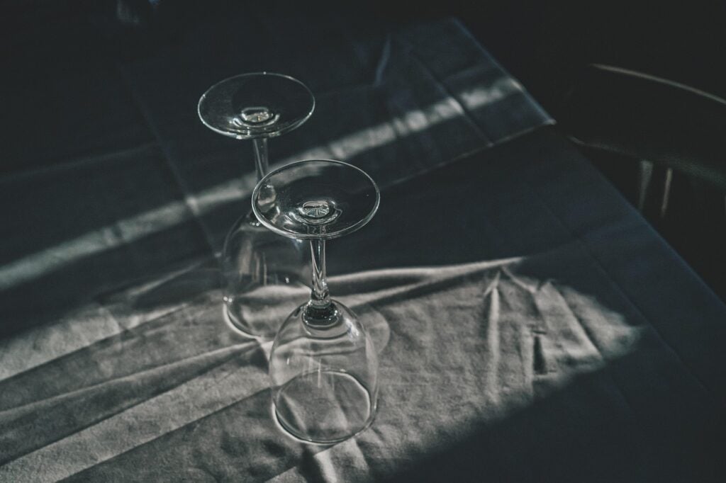 two stemmed glasses upside down on a white tablecloth