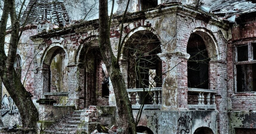 the front porch of an abandoned house, with ornate arches and stone steps. a large tree blocks part of the entrance