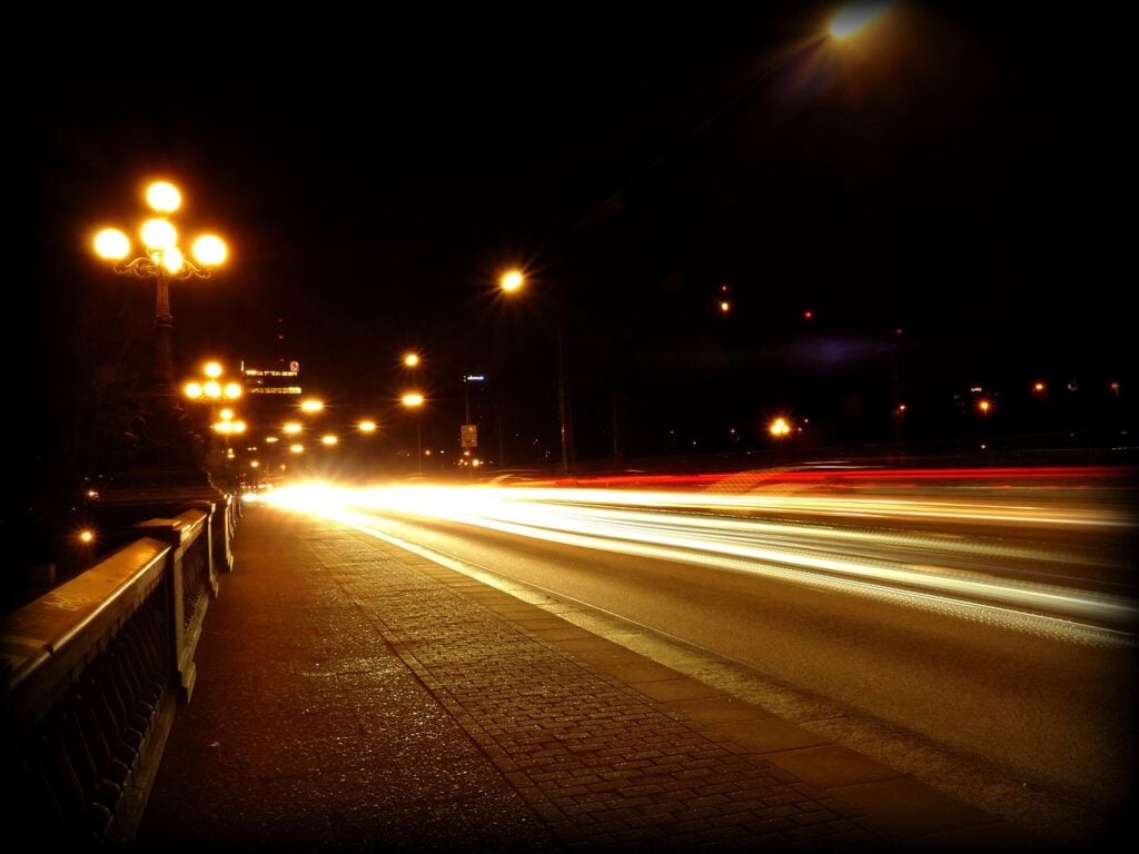 a road at night with lights streaking down it from automobile headlights
