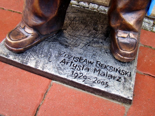feet of a statue with the words "zdislaw beksinski, artysia malarz, 1929-2005" written on its base