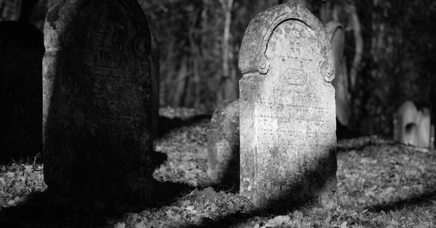 a black and white photo of a very old headstone in a graveyard