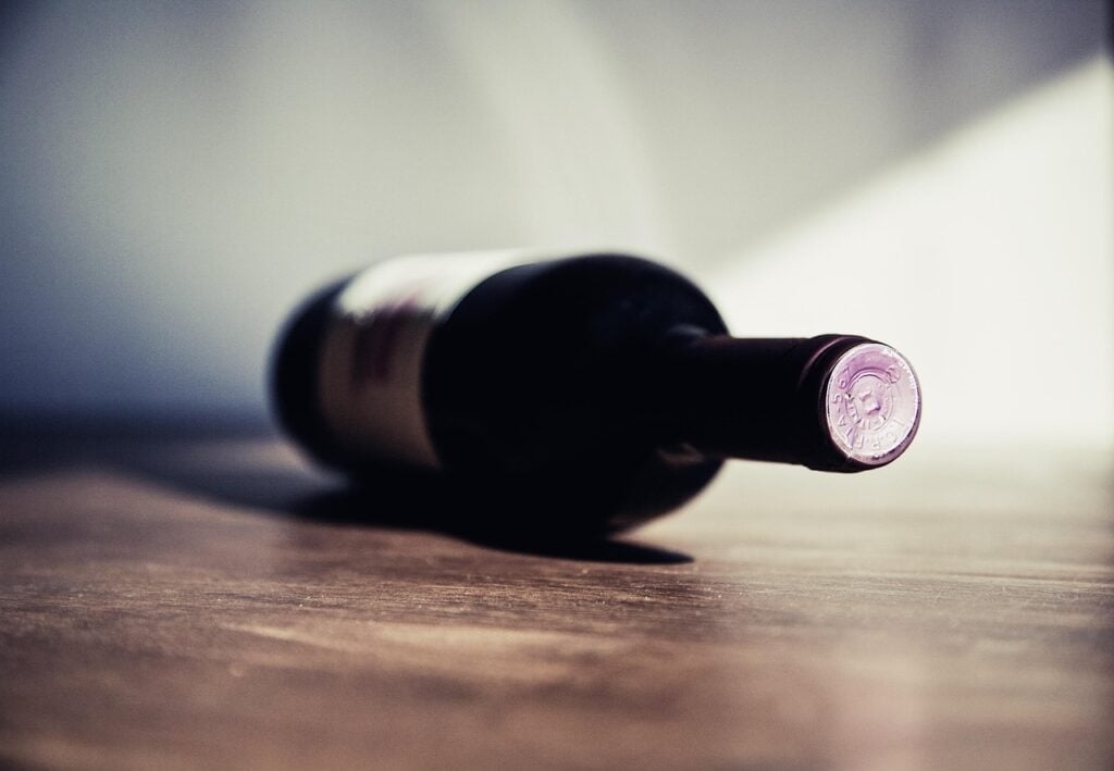 a bottle of red wine lying on its side on a wood surface