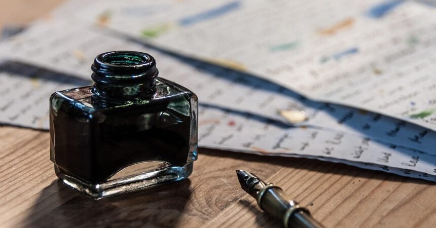 a fountain pen, a bottle of ink, and some scattered papers with writing on them on a wood surface