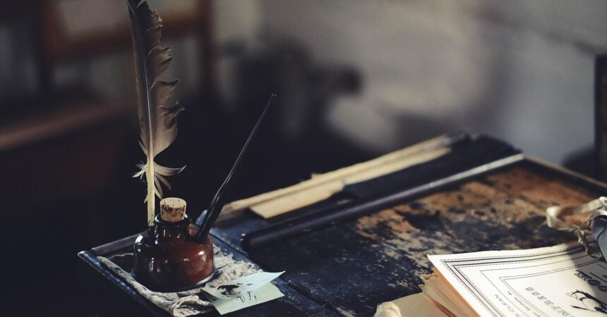 a bottle of ink and a quill pen on an old wooden desk