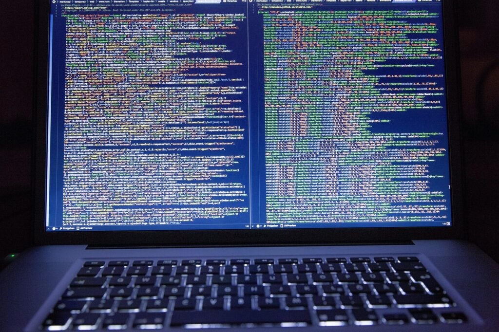 a laptop computer open with a screen full of complicated looking code
