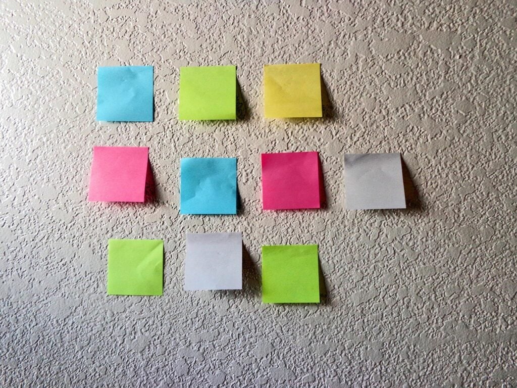 10 multi-colored sticky notes arranged in three lines on a textured wall