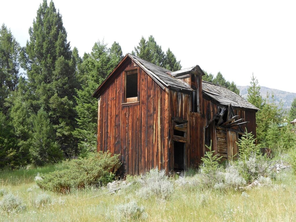 an abandoned wooden mill or barn type building in a hilly Montana landscape
